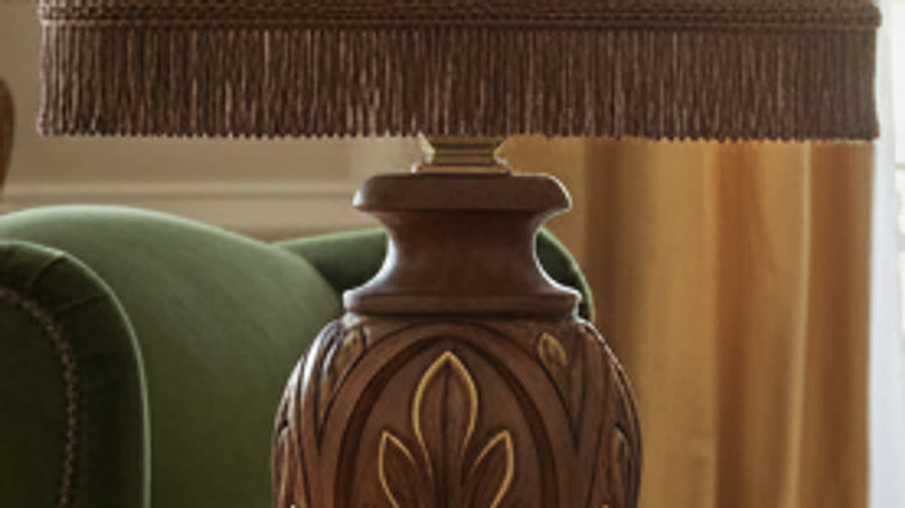 Render fotorealistico ambientato di «Intaglio a Foglia Oro — Paralume con Frangia», in Noce intagliato — illuminazione su misura Made in Italy
